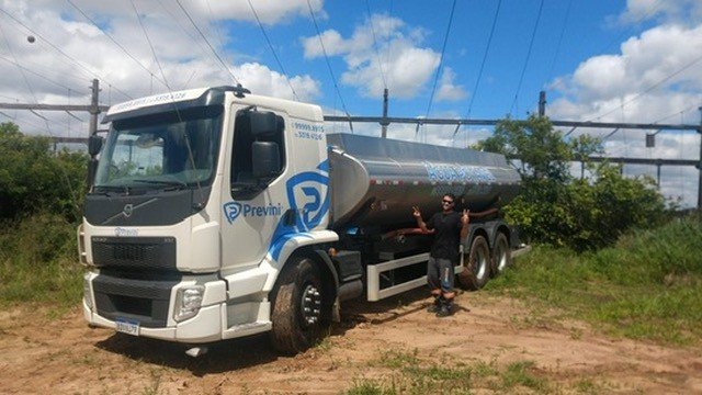 Caminhão de tanque metálico com marca Previni em área gramada.