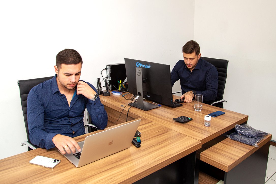 Dos personas trabajando en un escritorio; el logotipo de Previni se ve en un monitor.