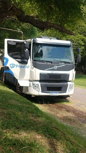Caminhão Volvo em passagem arborizada.