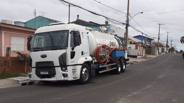 Caminhão em rua residencial com casas baixas.