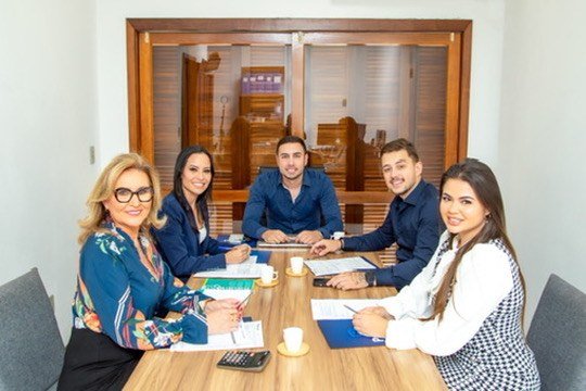 Grupo de pessoas sentado à mesa em escritório.