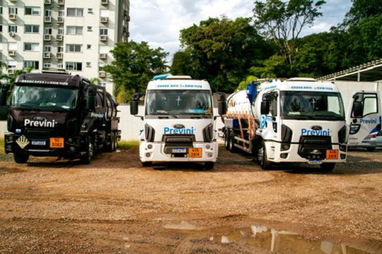 Três caminhões da frota Previni vistos de frente em pátio.